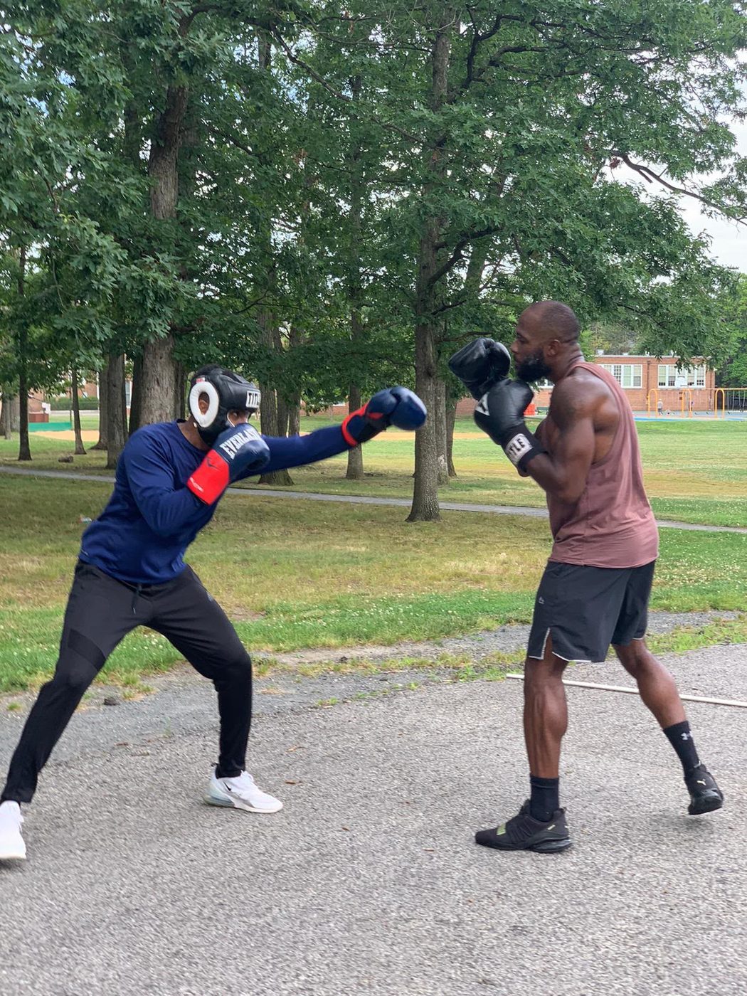 Coach Tae holding pads for a client during outdoor boxing training